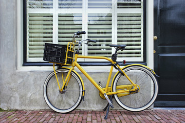 Fototapeta na wymiar Yellow retro transport bike parked against a renovated house.