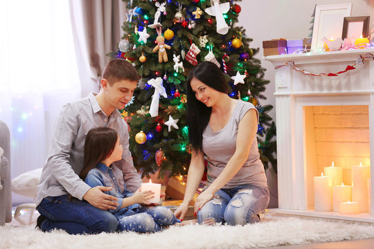 Happy family together hold candle in hands in the decorated Christmas room