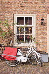Fototapeta na wymiar White classic bicycle parked against brick wall of an ancient house, Heusden, Netherlands.