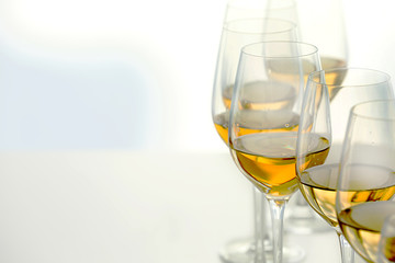 Wineglasses with white wine on wooden table on bright background
