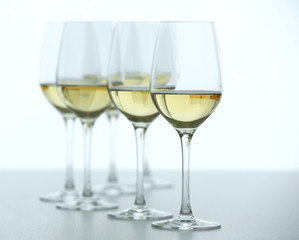 Wineglasses with white wine on wooden table on bright background