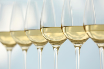 Wineglasses with white wine on wooden table on bright background