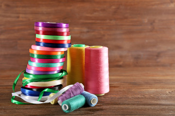 Spools of color ribbon, thread on wooden background