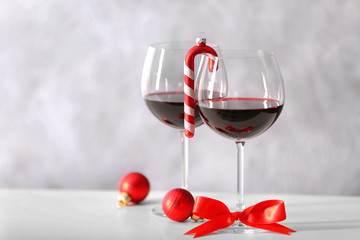 Two glasses of wine with christmas accessories on grey wall background