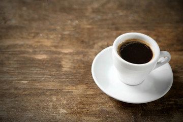 Cup of coffee and coffee grains on wooden background