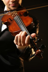 Musician plays violin on black background, close up