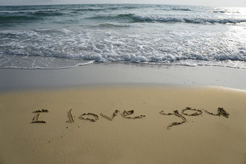 Handwriting word I love you written  in the sand