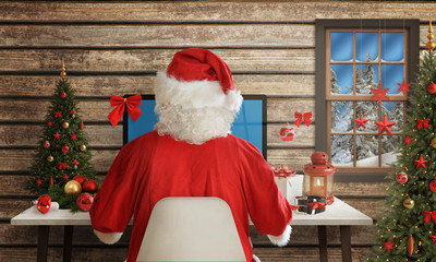 Santa Claus responds to letters on a computer for Christmas. Gifts, Christmas tree and decorations...