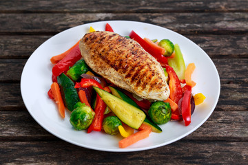 Grilled chicken fillet, breast with cooked vegetable  on plates