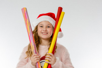 Mädchen mit Weihnachtsmütze hält Geschenkpapier hoch