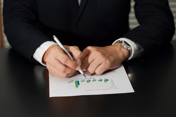 Businessman's Hand holding a pen pointing to the bar graph of Bu