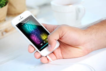 Music smartphone in male hand, on light background