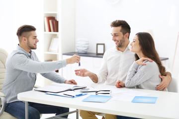 Fototapeta premium Happy family with estate agent, in bright office