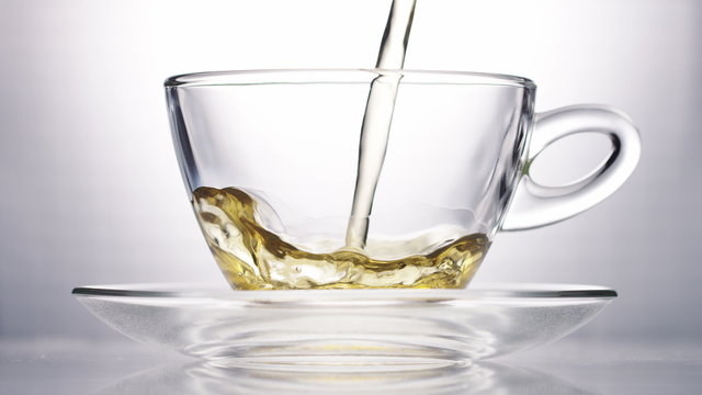 4K Hot chai tea poured into a clear glass cup, in slow motion
