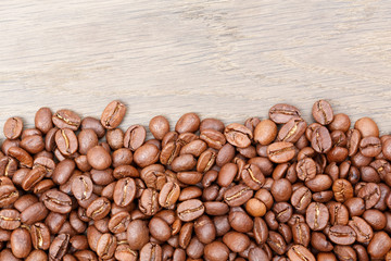 Coffee beans on the brown wooden background.