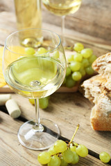 Still life of wine, grape, cheese and bread on rustic wooden background