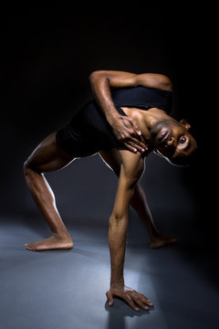 Black male dancer practicing warm up exercises for flexibility