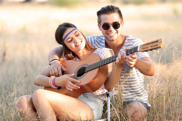 Attractive couple playing guitar, outdoors