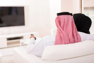 rear view of muslim couple watching tv
