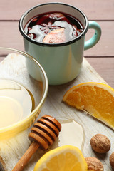 Mulled wine in a mug with citruses on wooden background, close up