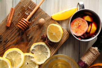 Delicious mulled wine in a mug with citruses on decorated wooden background, close up