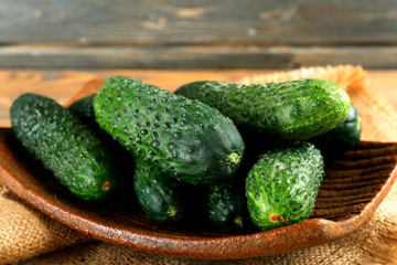 Fresh cucumbers in rustic bowl on  wooden background