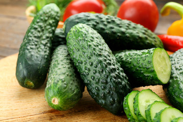 Composition of cucumbers, tomatoes and sweet peppers circles on wooden background, close up