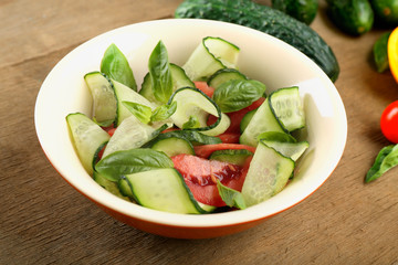 Vegetable salad with cucumbers on wooden background