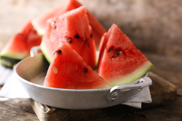 Sliced watermelon in metal bowl on wooden background