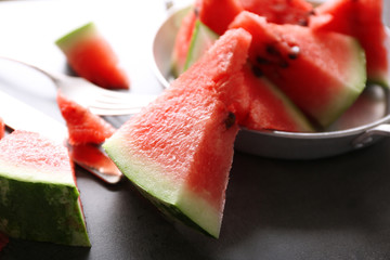 Sliced watermelon in metal bowl on grey background, close up