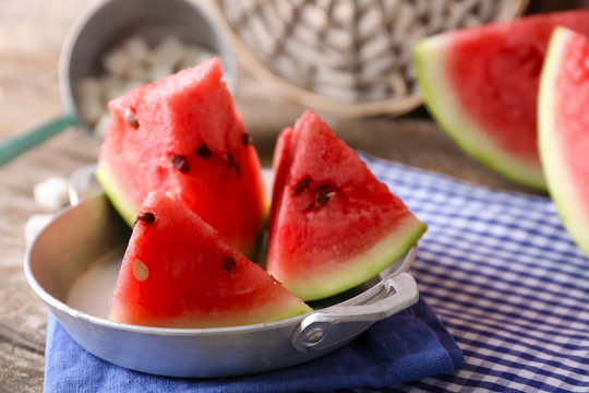 Sliced watermelon in metal bowl on decorated wooden background