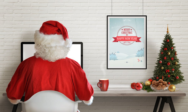 Santa Claus responds to letters on a computer for Christmas. Gifts, Christmas tree and decorations on table.