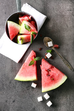 Sliced watermelon in metal bowl with sugar on grey background, close up
