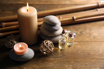 Decorated composition with candles, pebbles and bamboo on wooden background