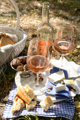 Picnic theme - rose wine, cheese, baguette and nuts outdoors