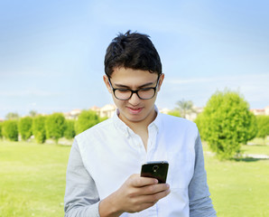 Young man with eyewear in garden looking in smart phone.