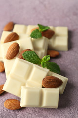 White chocolate pieces with nuts on color wooden background