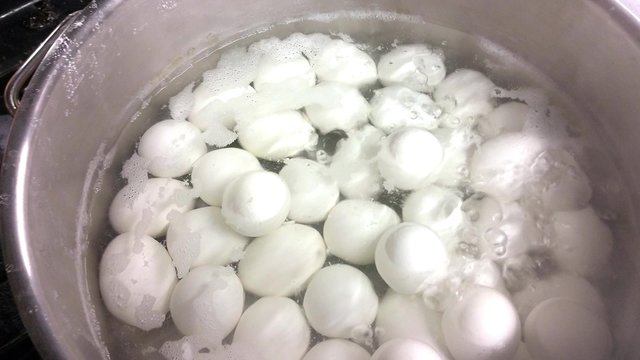 Boiling white chicken eggs, inside a big pot, at a restaurant kichen