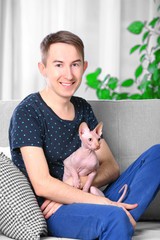 Young handsome man sitting with cat on couch at home