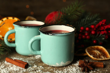 Decorated composition of mulled wine in mugs on wooden table