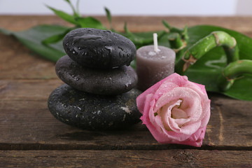 Fototapeta na wymiar Spa stones, a candle and a rose on wooden background