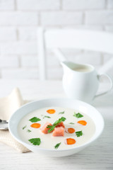 Delicious cream soup with salmon and carrot in white bowl