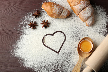 Heart of flour, croissant and spices on gray background
