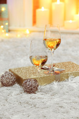 Wine glasses with Christmas decor on fireplace background