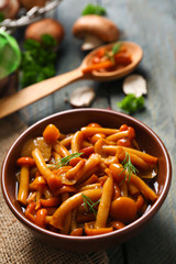 Delicious marinated mushrooms in bowl on wooden background