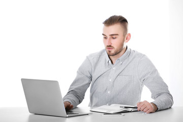 Businessman working with laptop on bright background