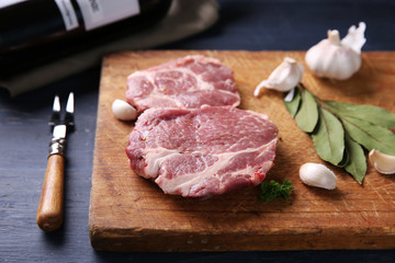 Marbled beef steak with bottle of wine and spices on wooden background