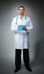 Portrait of a doctor with prescription board in hands  on grey background
