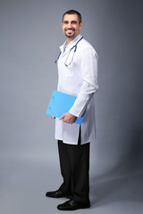 Portrait of a doctor with prescription board in hands  on grey background