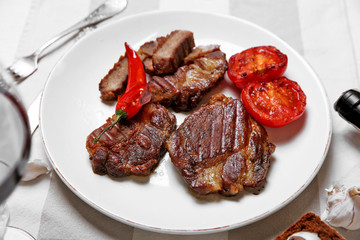 Roasted beef fillet and grilled vegetables on plate, on wooden background